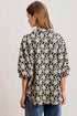 Woman wearing a black floral patterned shirt against a plain background