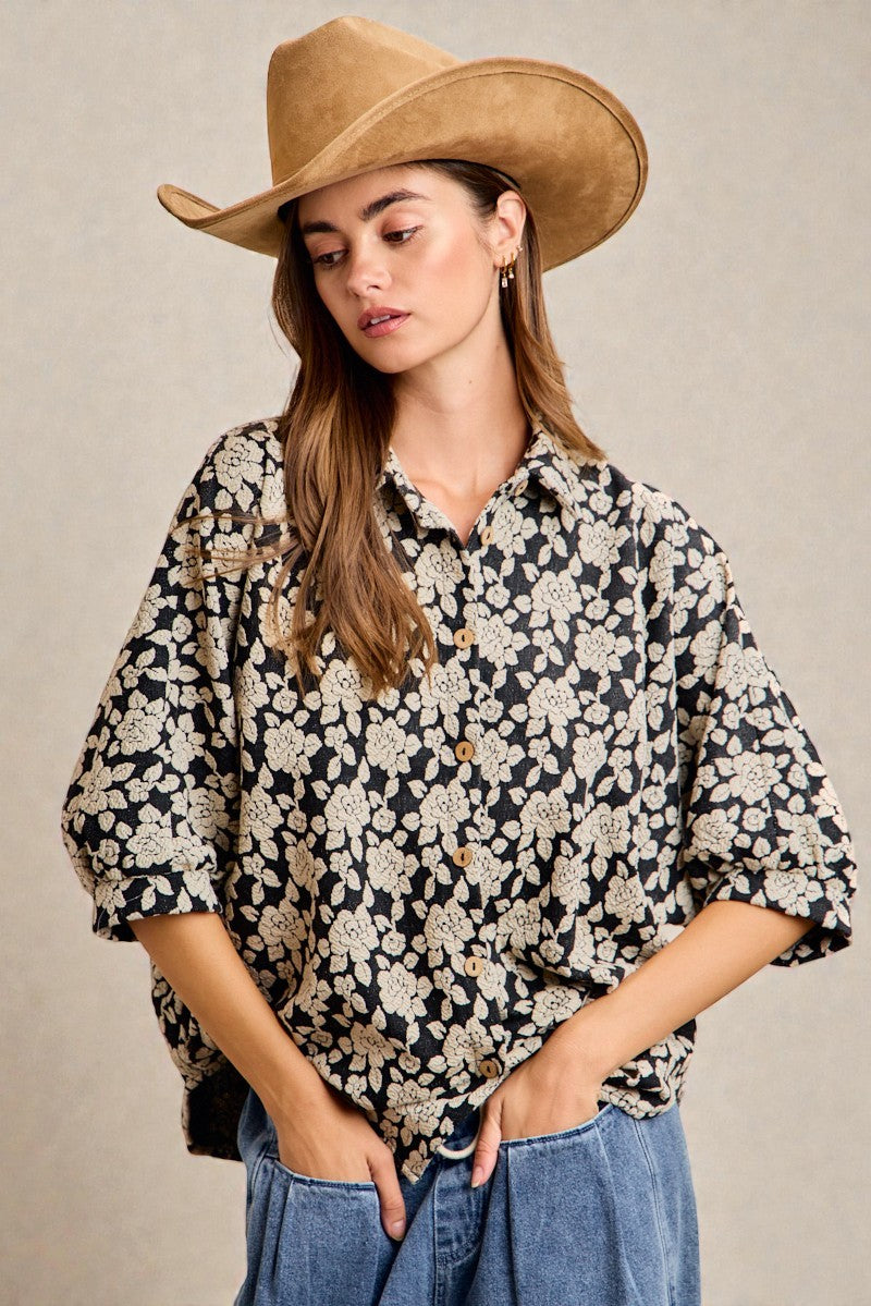 Woman wearing a floral blouse and cowboy hat against a beige background
