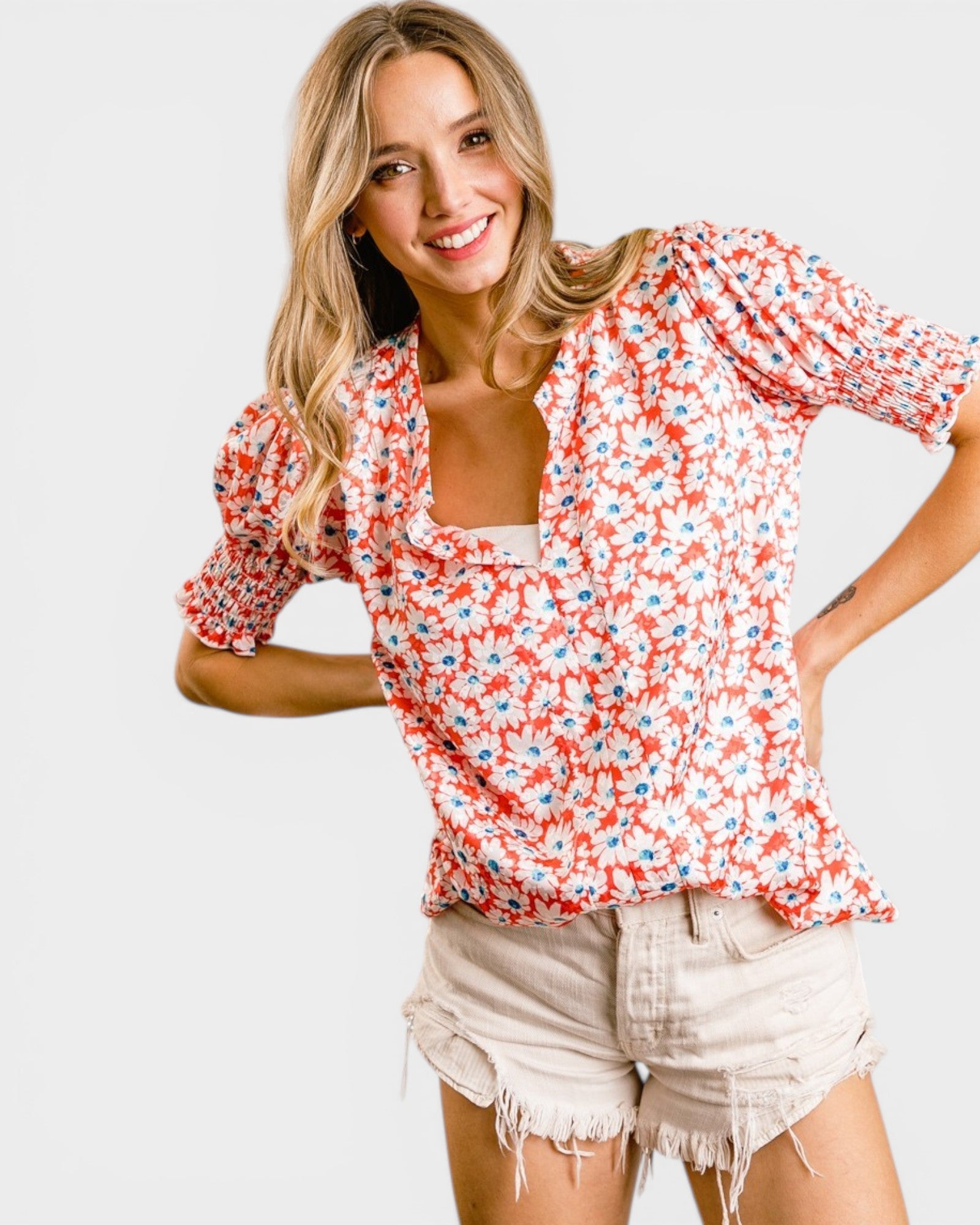 Woman wearing a floral blouse and shorts on a white background