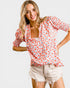 Woman wearing a floral blouse and shorts on a white background