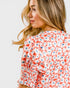 Woman wearing a red floral blouse on a white background