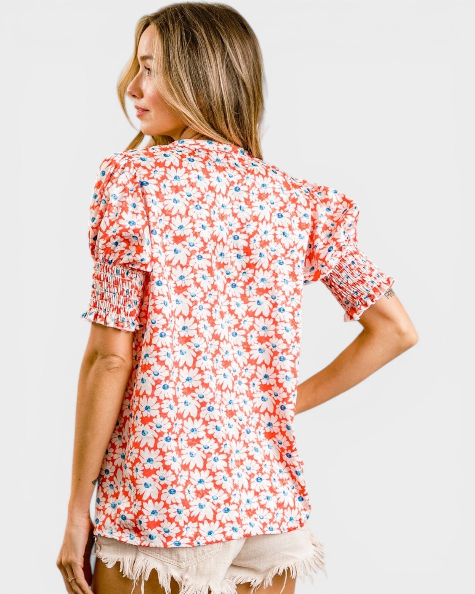 Woman wearing a red floral blouse on a plain background
