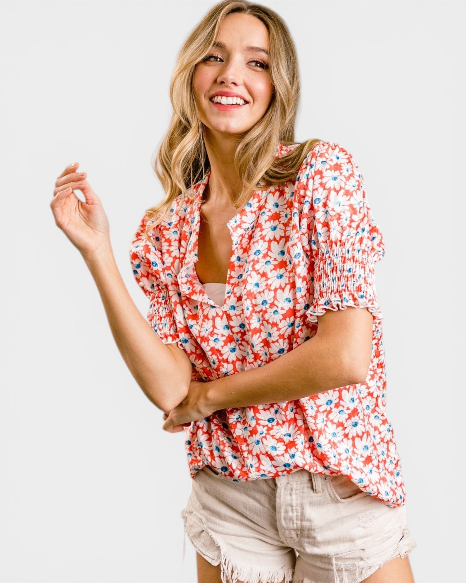 Woman wearing a red floral blouse and beige shorts on a white background