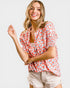 Woman wearing a red floral blouse and beige shorts on a white background