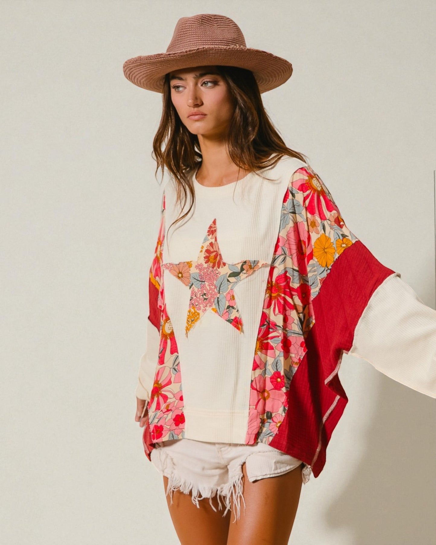 Woman wearing a floral kimono over a white shirt with a plain background