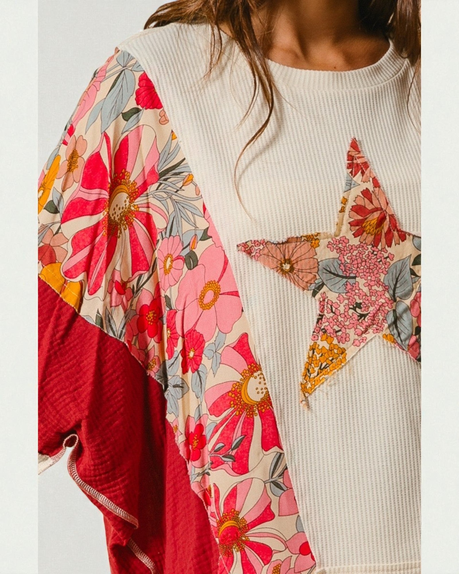 Person wearing a white sweater with colorful floral sleeves and a red skirt.