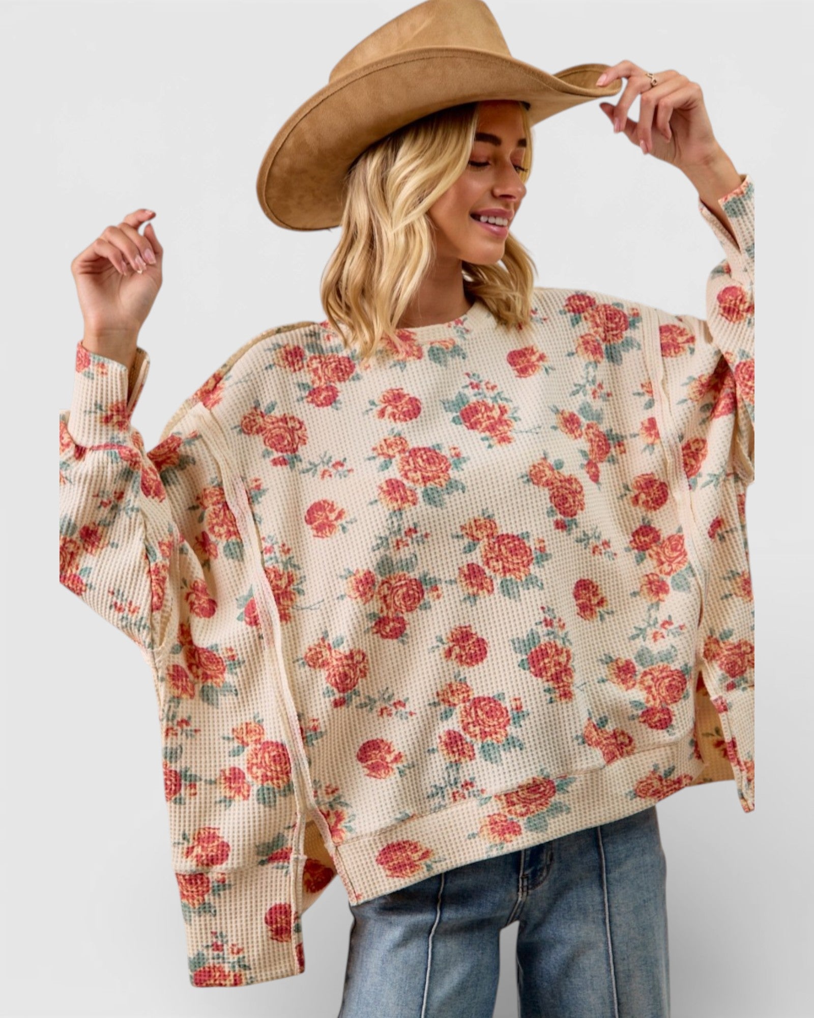 Woman wearing a floral poncho and wide-brimmed hat on a plain background