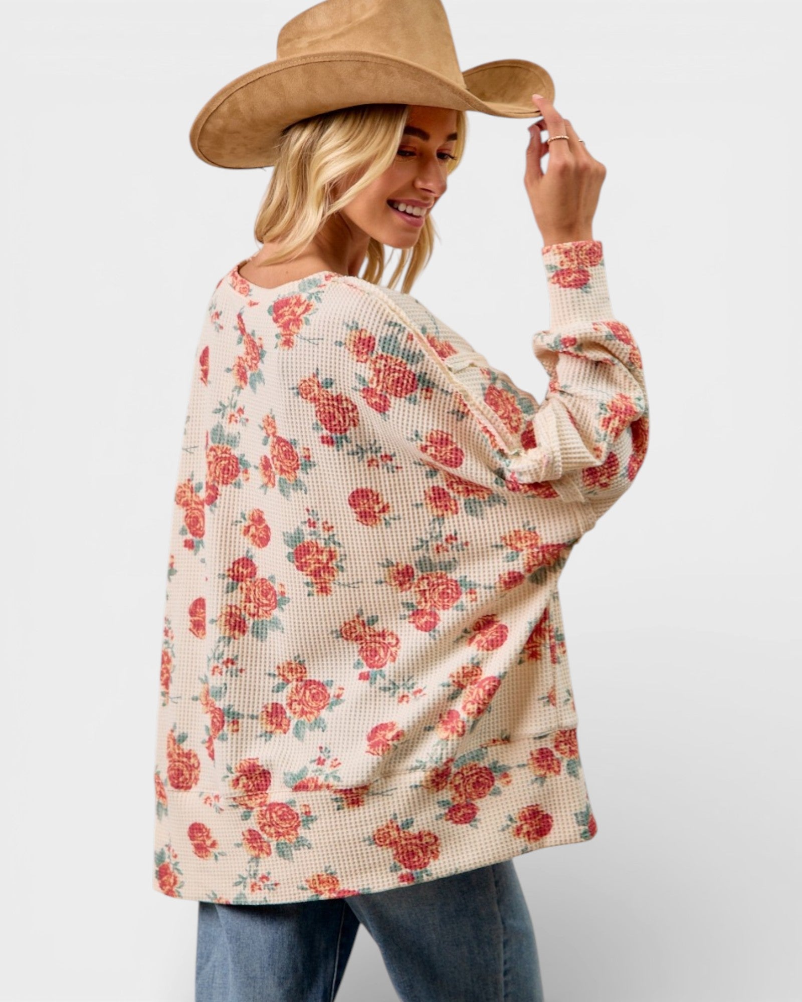 Woman wearing a floral sweater and wide-brimmed hat on a plain background