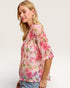 Woman wearing a floral blouse with a plain background