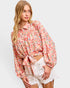 Woman wearing a floral blouse and white shorts on a plain background