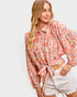 Woman wearing a floral blouse with rolled-up sleeves on a white background
