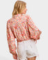 Woman wearing a floral blouse and white shorts on a light gray background