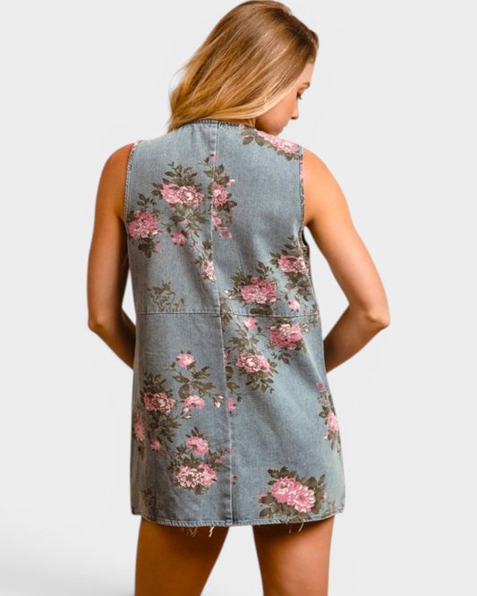 Woman wearing a denim dress with floral patterns on a plain background