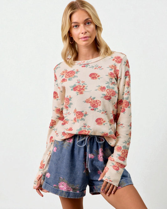 Woman wearing a floral long-sleeve top and denim shorts on a white background