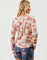 Woman wearing a floral long-sleeve top and denim shorts on a white background