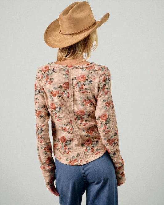 Person wearing a floral sweater and brown hat on a plain background