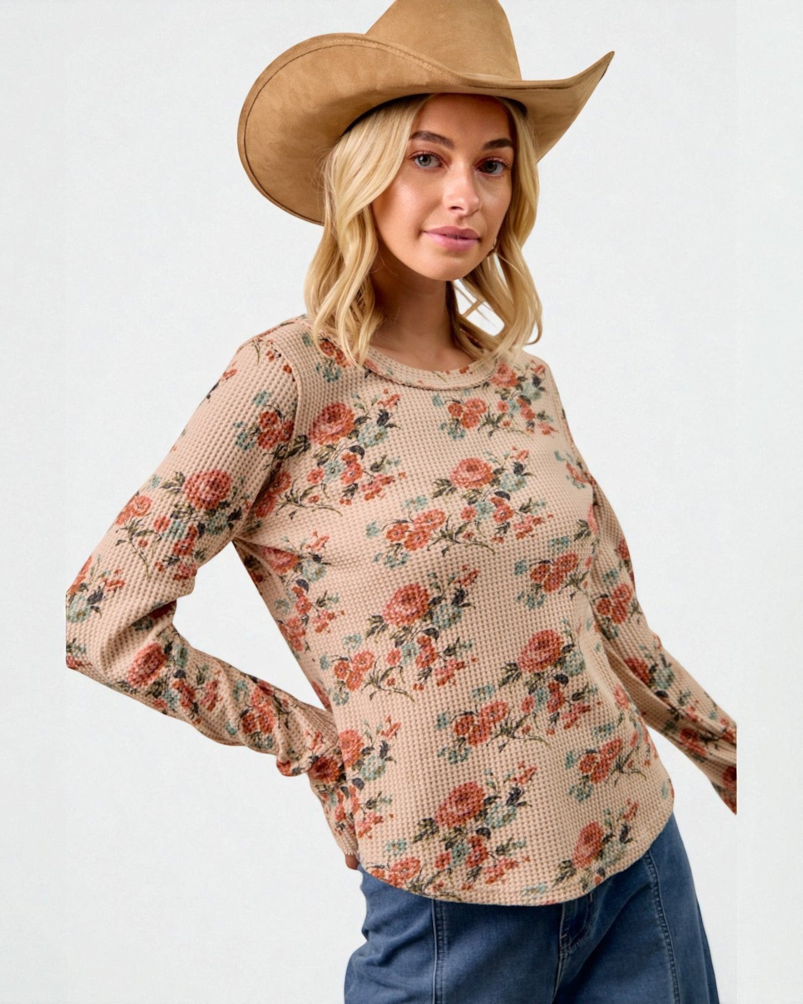 Woman wearing a floral long-sleeve top and cowboy hat on a white background