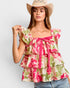 Woman wearing a floral top and cowboy hat on a plain background