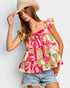 Woman wearing a floral top and denim shorts with a straw hat on a light gray background