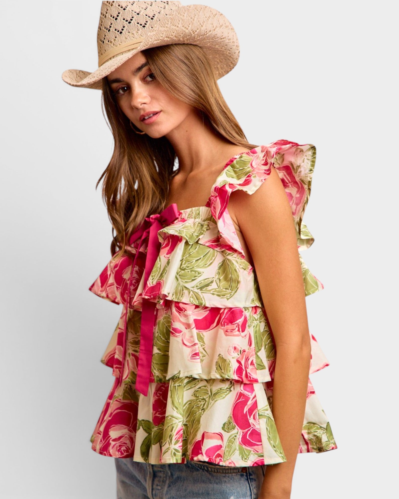 Woman wearing a floral top and cowboy hat on a plain background