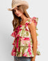 Woman wearing a floral top and cowboy hat on a plain background