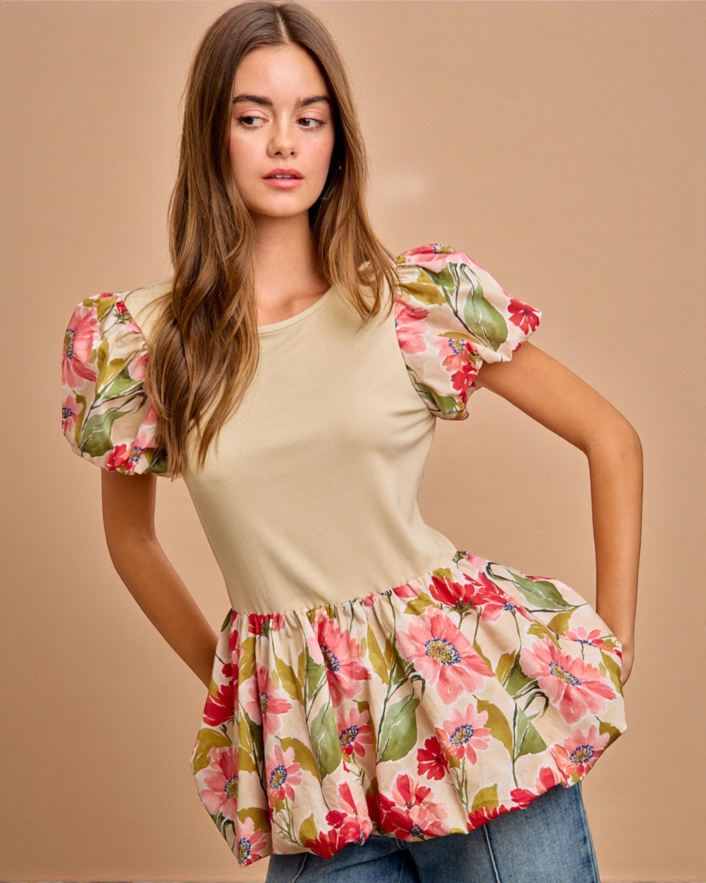 Woman wearing a beige top with floral sleeves and bottom on a beige background