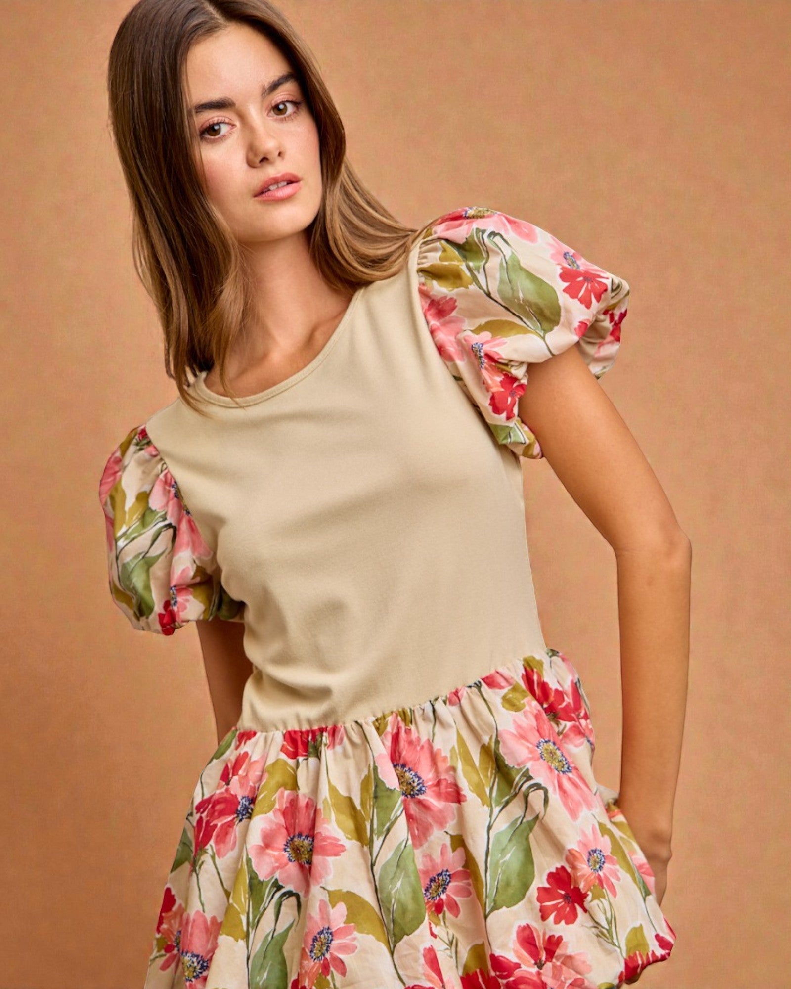 Woman wearing a cream top with floral sleeves and skirt against a beige background