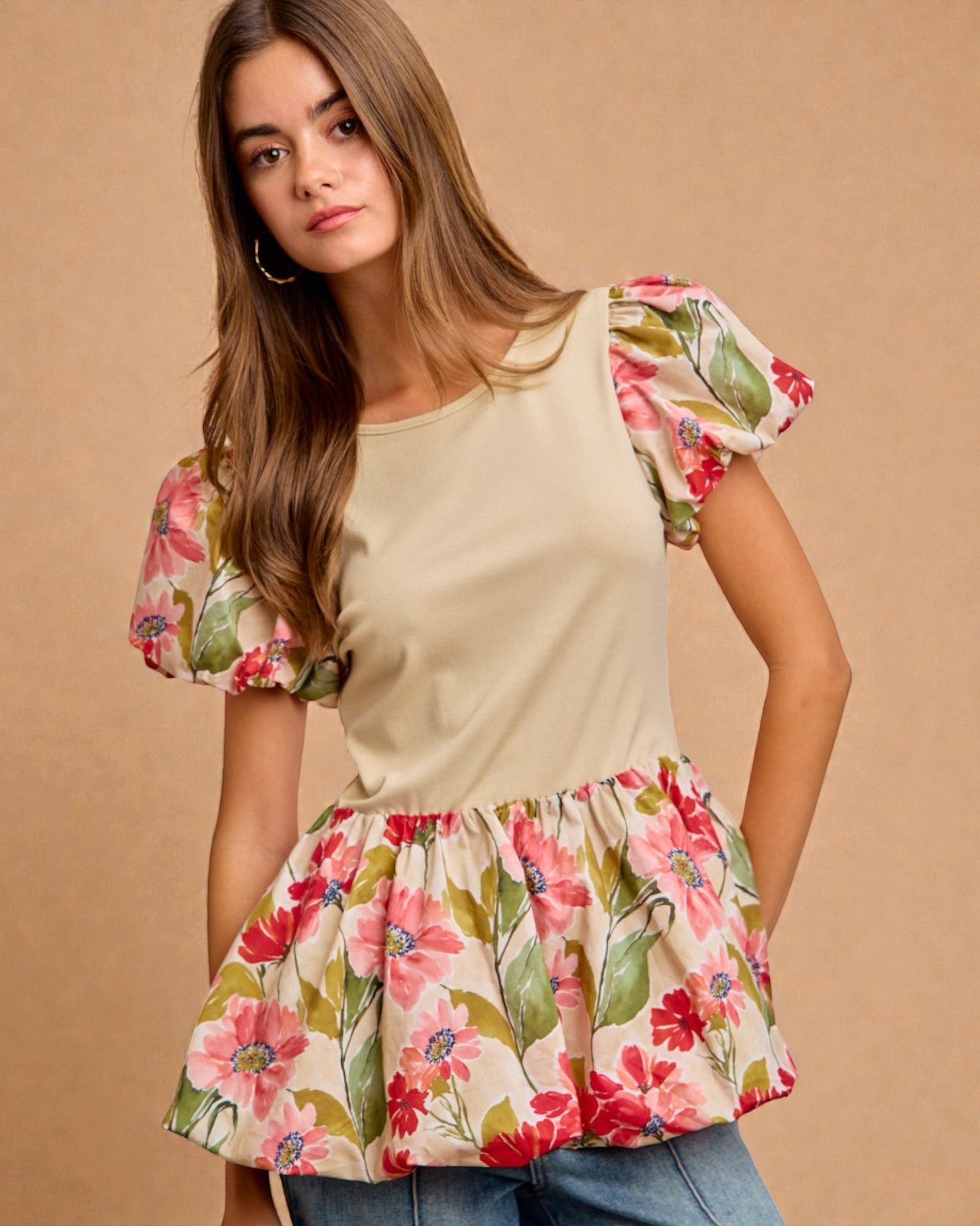Woman wearing a beige top with floral sleeves and bottom on a brown background