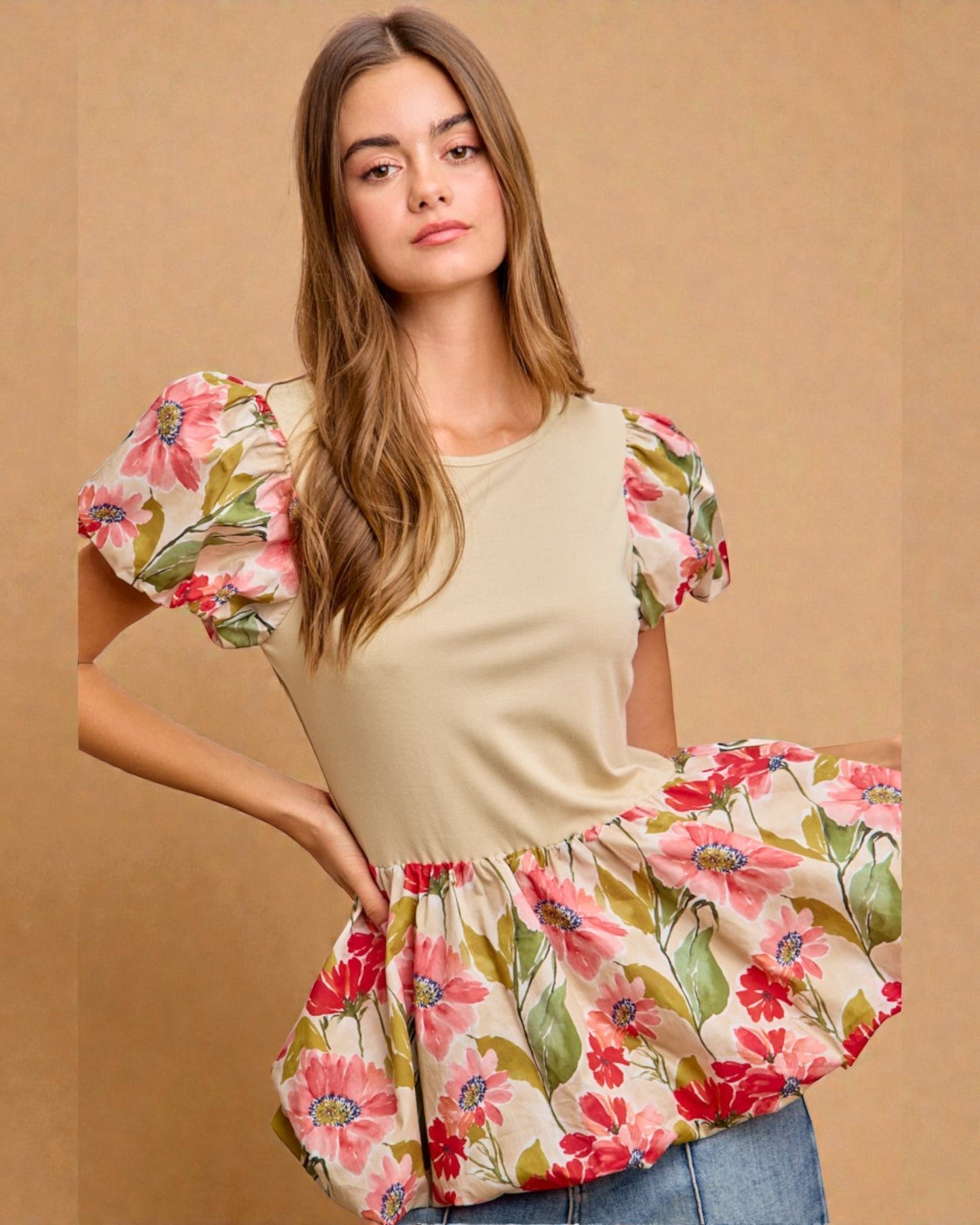 Woman wearing a beige top with floral sleeves against a beige background