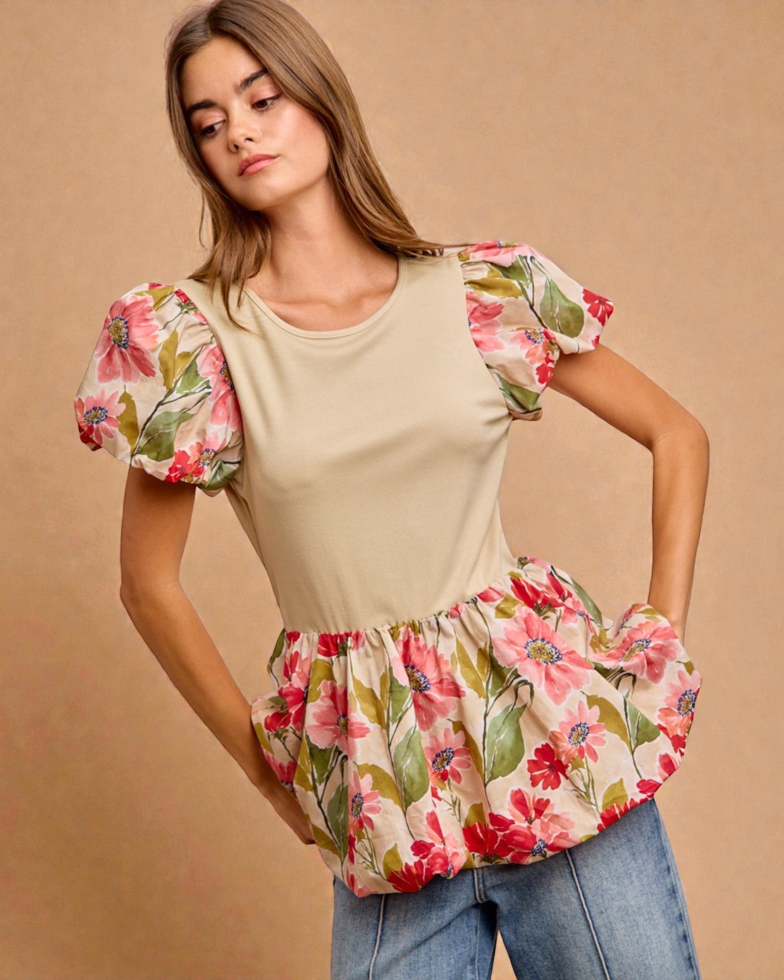 Woman wearing a beige top with floral sleeves and bottom on a beige background