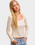 Woman wearing a long-sleeve top with a subtle pattern on a plain background