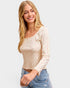 Woman wearing a long-sleeve top with a subtle pattern on a plain background