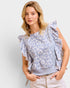 Woman wearing a light blue floral blouse with ruffled sleeves against a plain background