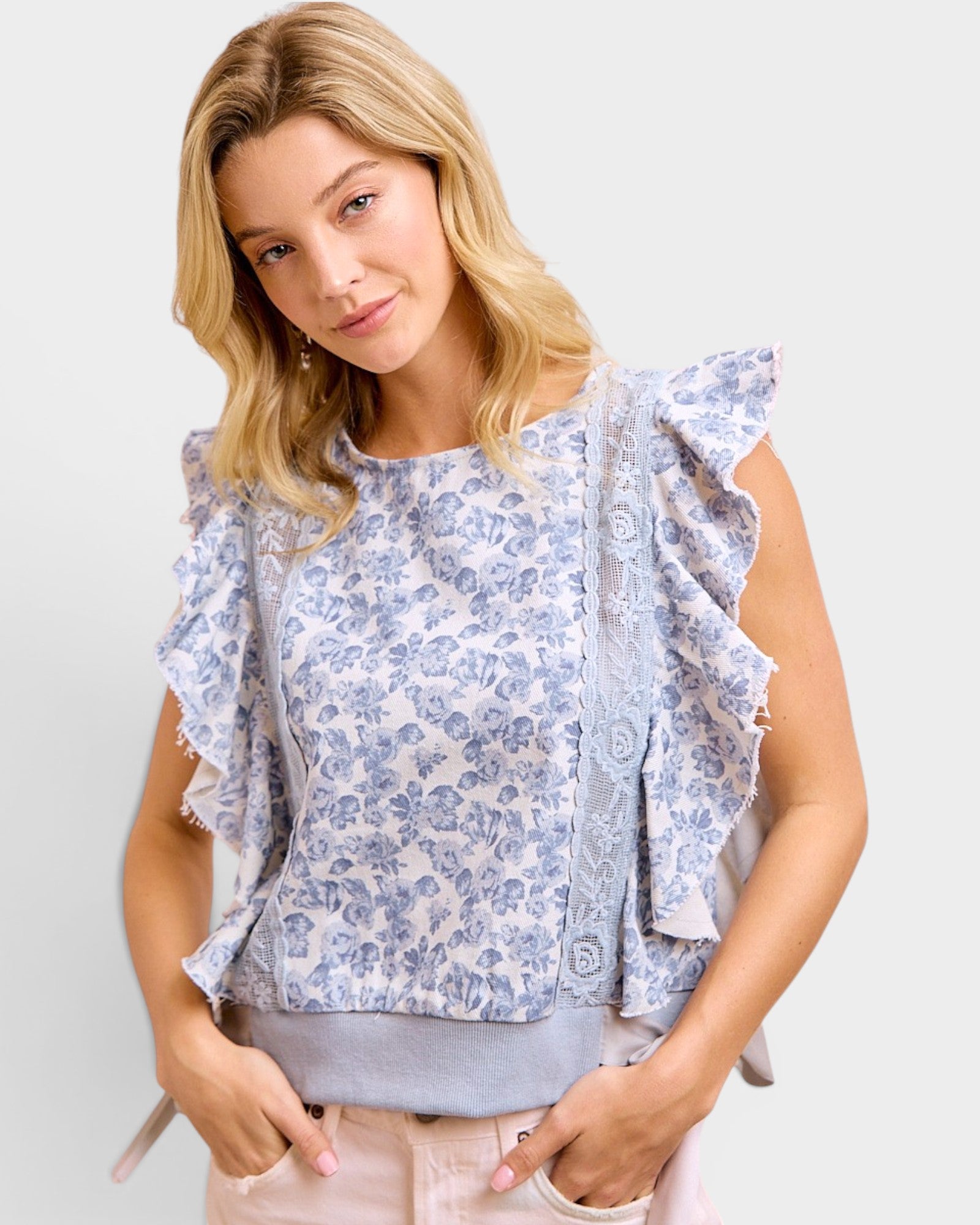 Woman wearing a floral blouse with ruffled sleeves against a plain background