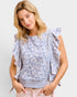Woman wearing a floral blouse with ruffled sleeves against a plain background