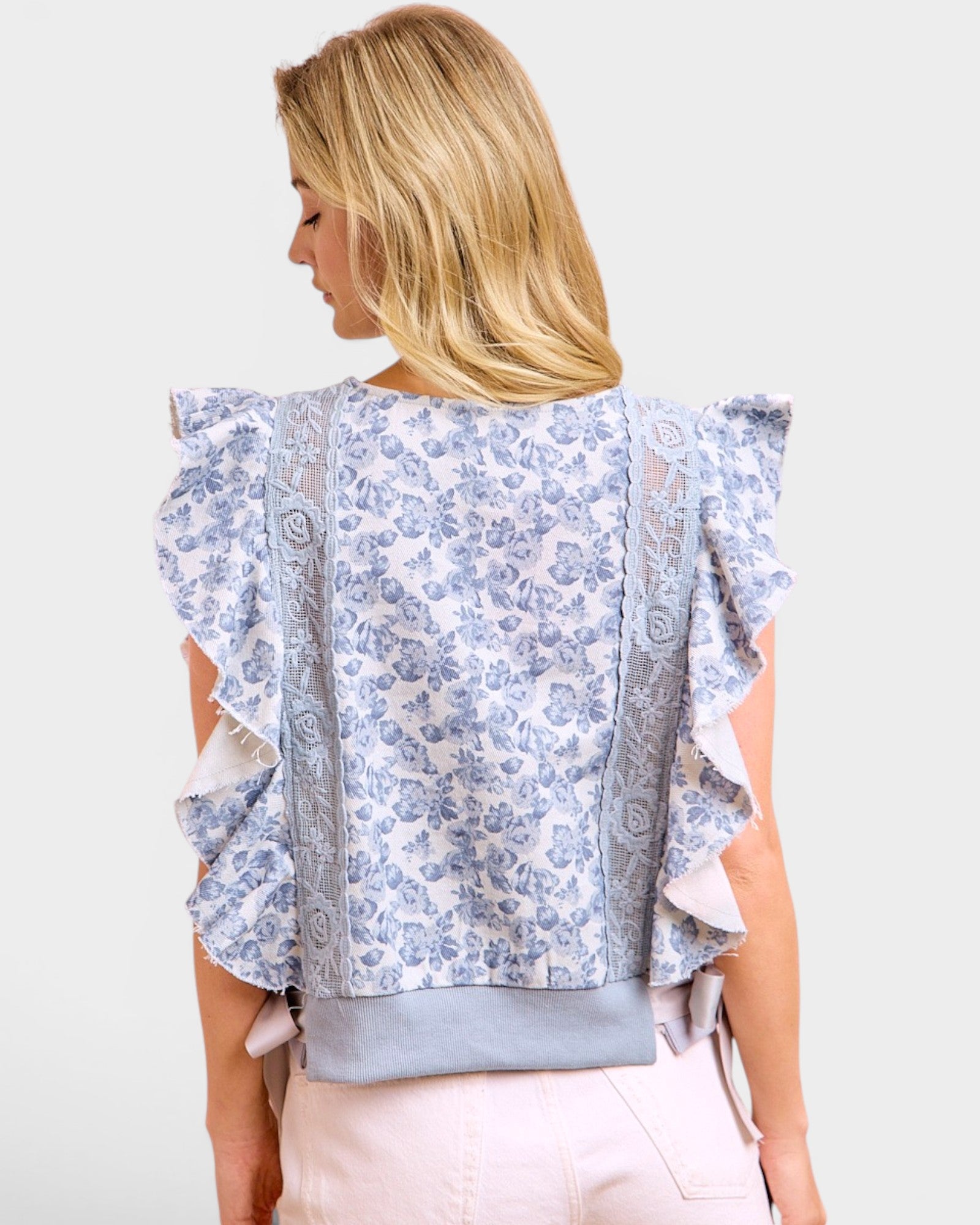 Woman wearing a floral blouse with ruffled sleeves on a white background