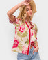 Woman wearing a floral sleeveless top with a straw hat on a plain background