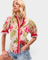 Woman wearing a floral blouse with puff sleeves against a plain background