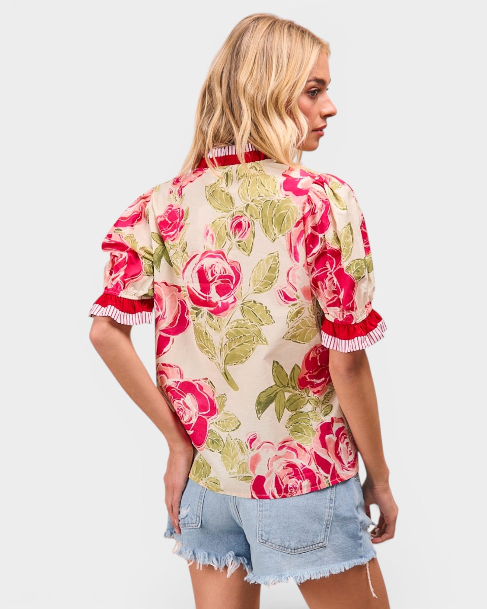 Woman wearing a floral blouse with red roses on a plain background