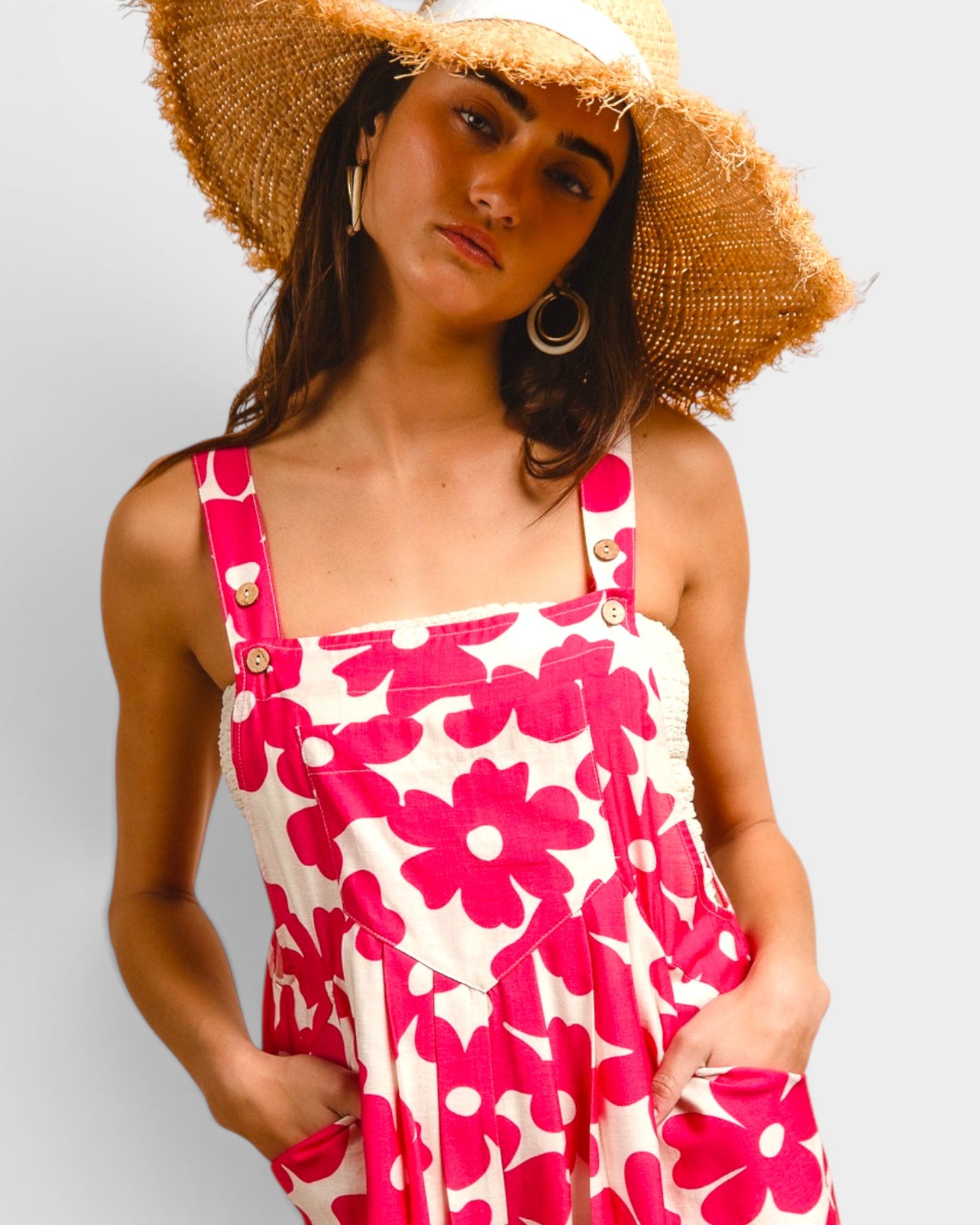 Woman wearing a pink floral dress and straw hat against a light background