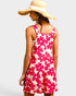 Woman wearing a pink floral dress and straw hat on a light gray background
