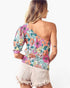 A woman shown from the back wearing a one-shoulder floral print top with puff sleeves and light beige frayed denim shorts against a plain white background.