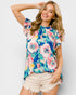 Woman wearing a colorful floral blouse against a white background