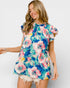 Woman wearing a colorful floral dress against a plain background