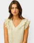 Woman wearing a light-colored top with ruffled sleeves on a plain background