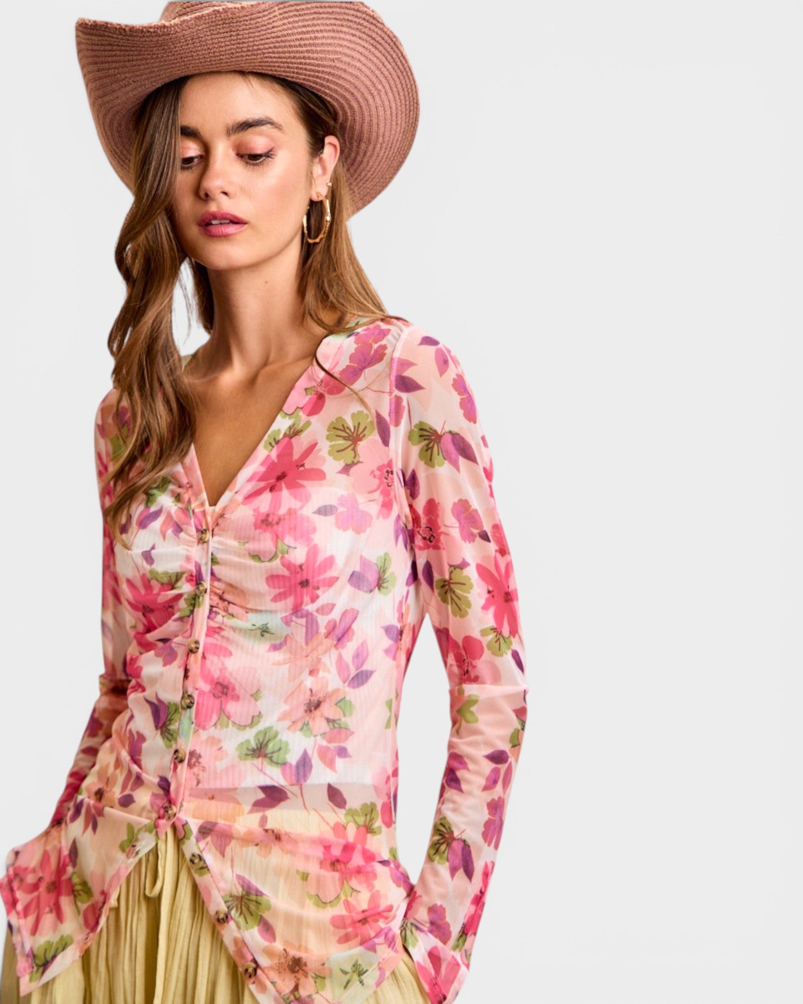 Woman wearing a floral dress and wide-brimmed hat on a plain background