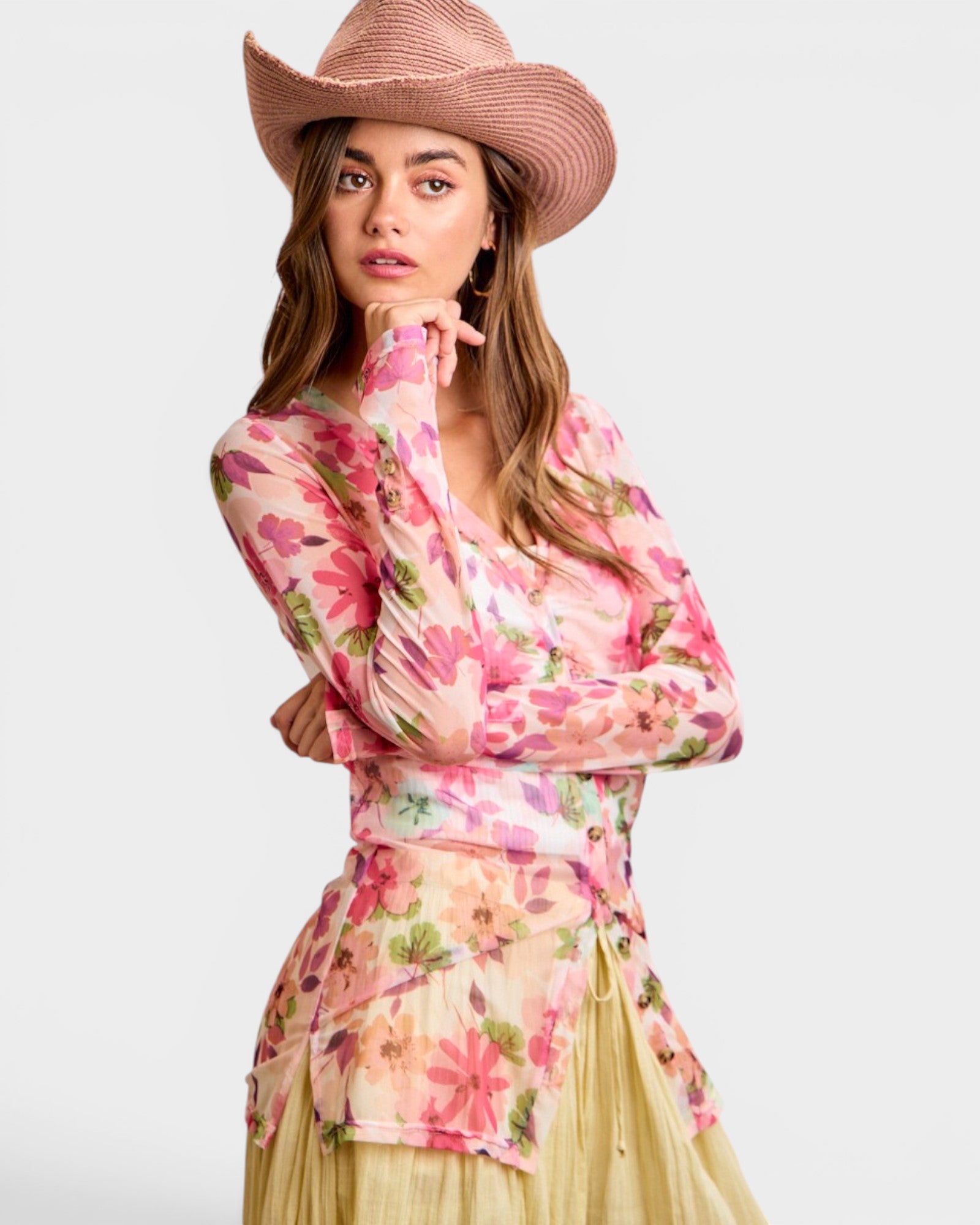 Woman wearing a floral top and straw hat on a white background