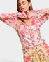 Woman wearing a floral pink and green top with long sleeves on a white background