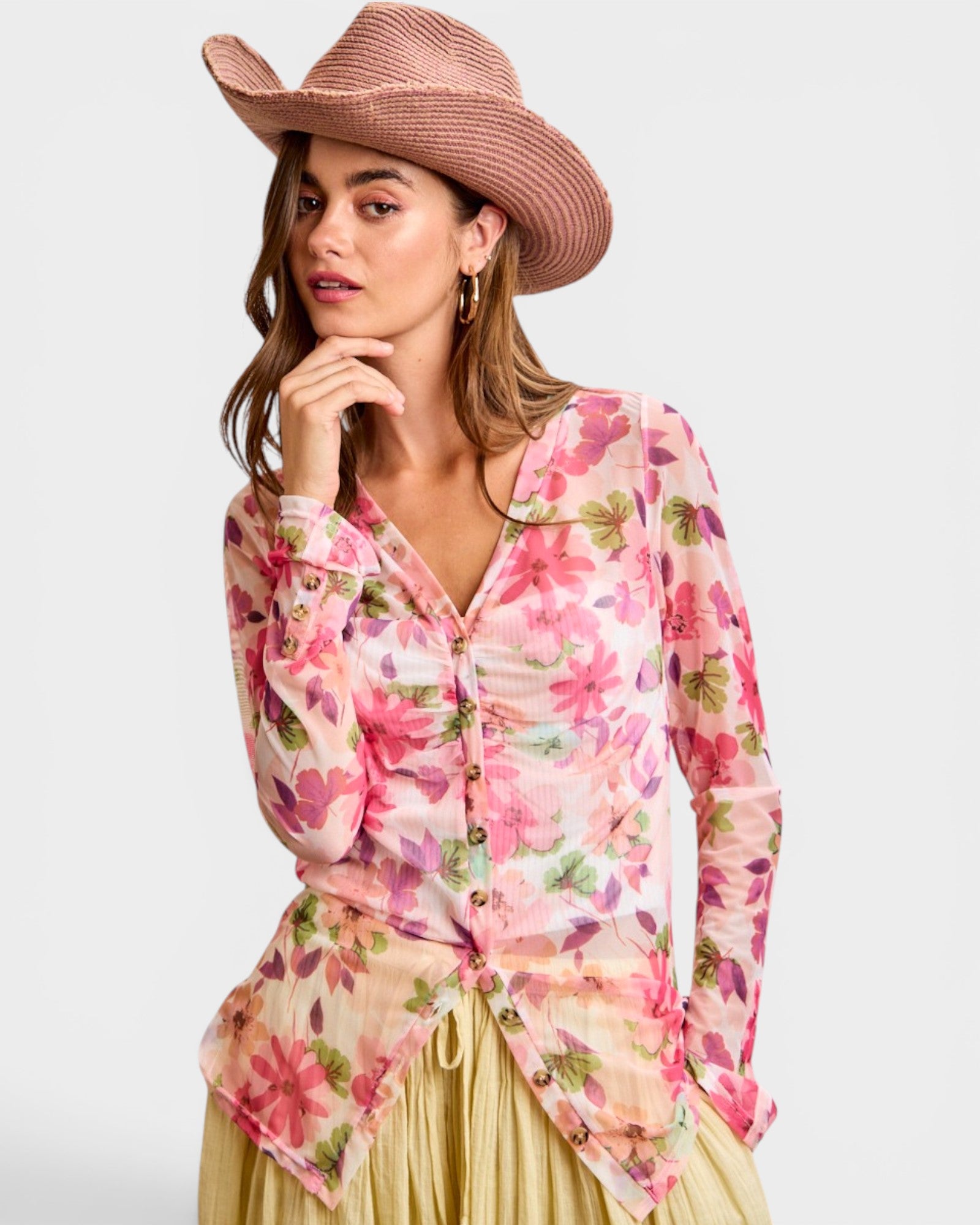Woman wearing a floral blouse and pink cowboy hat on a white background