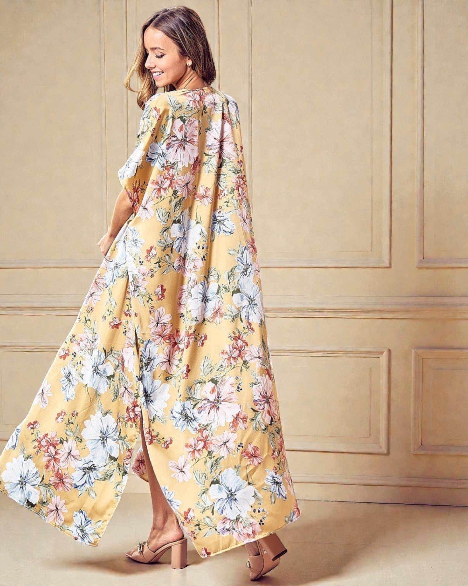 Woman wearing a long, floral-patterned dress against a beige wall.